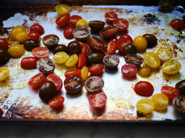 multi-color cherry tomatoes halved and arranged on a baking sheet drizzle with olive oil
