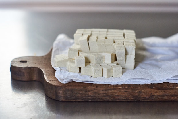 small cubes of tofu arranged on a paper towel lined cutting board