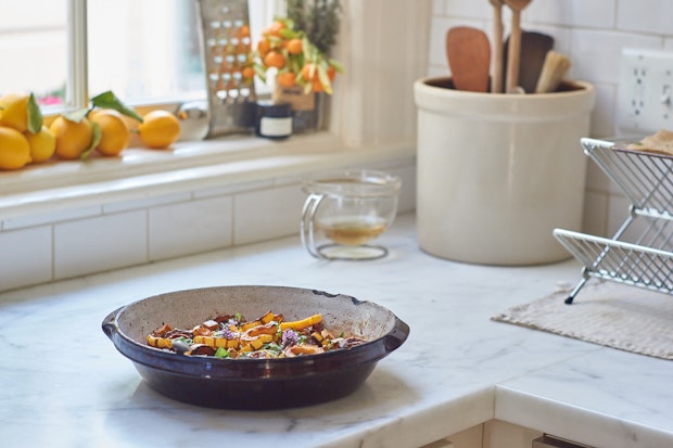 kitchen scene with serving bowl of roasted winter squash on a marble countertop