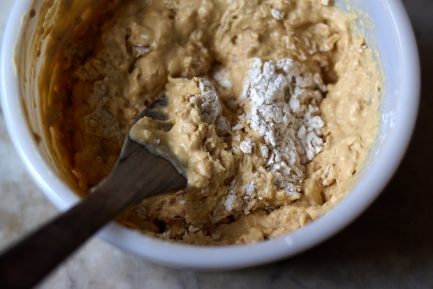 combining wet ingredients with dry ingredients in a bowl resulting in oatmeal muffin batter
