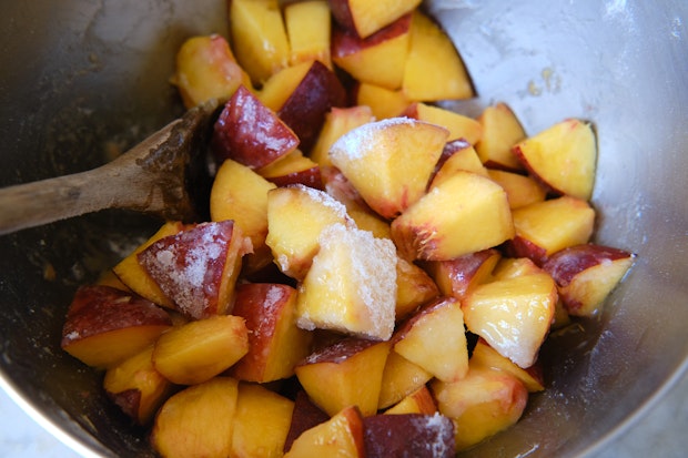 tossing peached in bowl with sugar