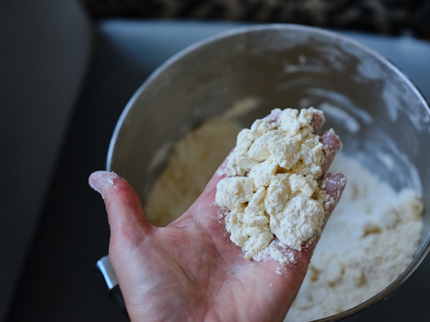 kawałki masła pokryte mąką w dłoni piekarza