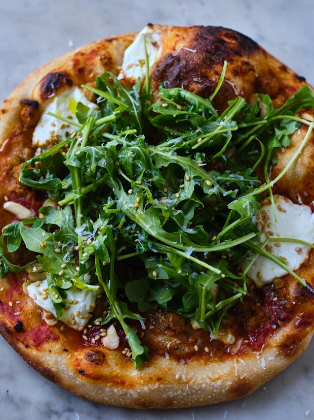 An example of a favorite pizza topping idea - marinara, arugula, and other ingredients on a freshly baked pizza