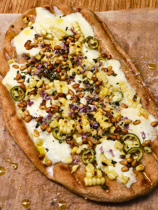 grilled pizza topped with mozzarella, corn, jalapeno, and pine nuts
