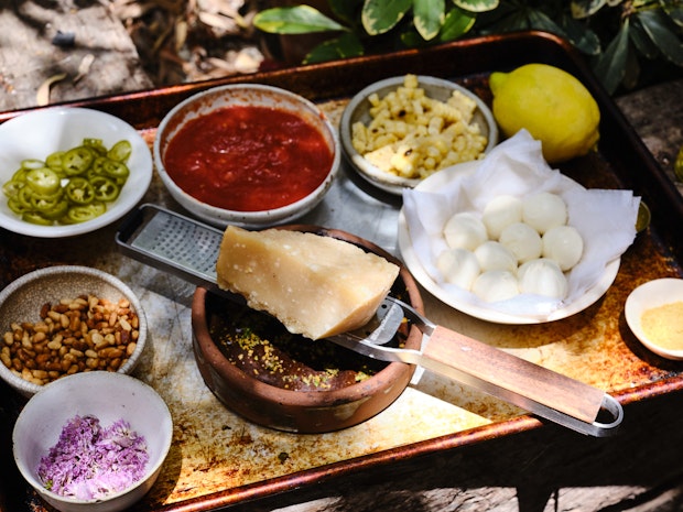 Tray filled with pizza topping ideas like mozzarella, pine nuts, corn and parmesan cheese