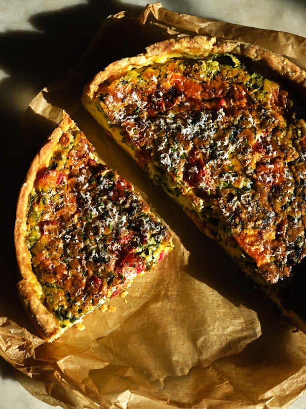 a quiche sliced into wedges on a sheet of parchment paper