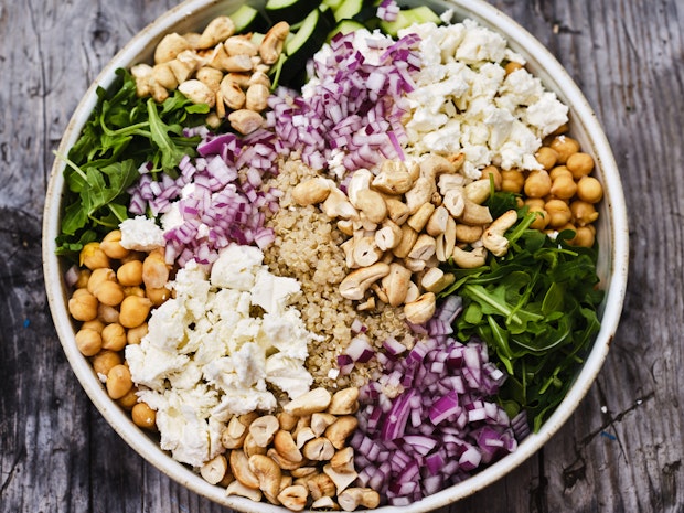 quinoa, cashews, red onions, feta, and arugula in a bowl