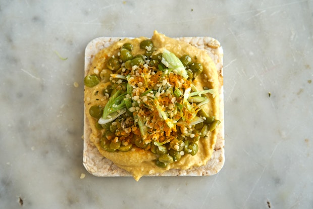 rice cracker topped with hummus, mung beans, and scallions