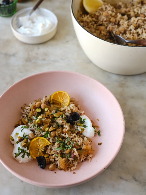 a pot of rice pilaf served on a table with bowls and yogurt