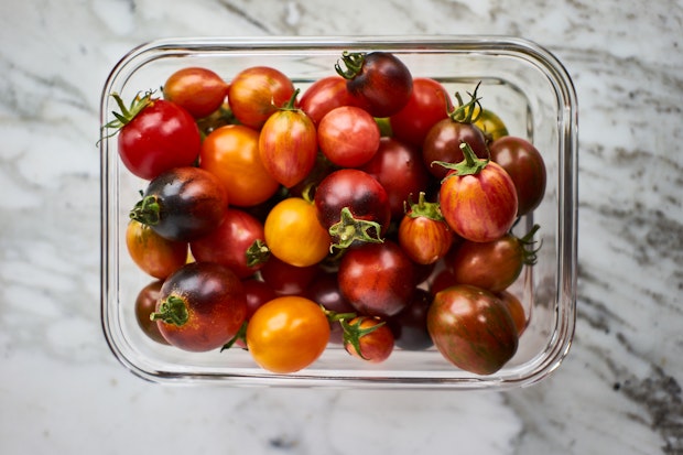 different color cherry tomatoes piled in a container