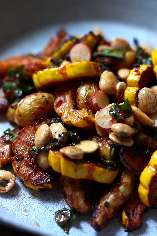 roasted delicata squash on a platter along with potatoes, kale, and almonds