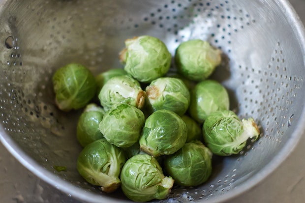 Brussels sprouts being washed in a sink