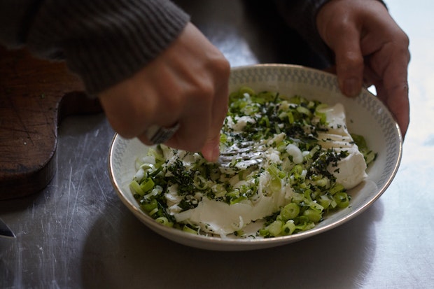 Smashing herbs into cream cheese with a fork