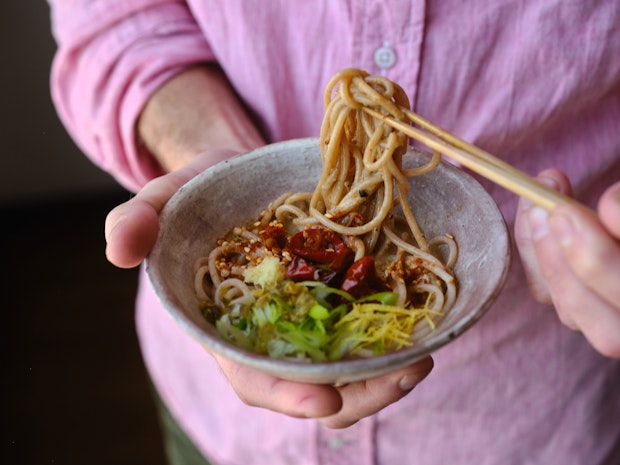 eating sesame noodles with chopsticks from a bowl