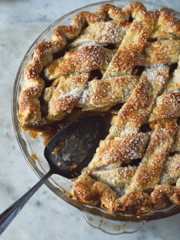 an apple pie with lattice crust in a glass pie dish with a wedge removed