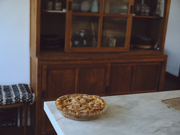 a full apple pie cooling on a countertop after baking in a kitchen