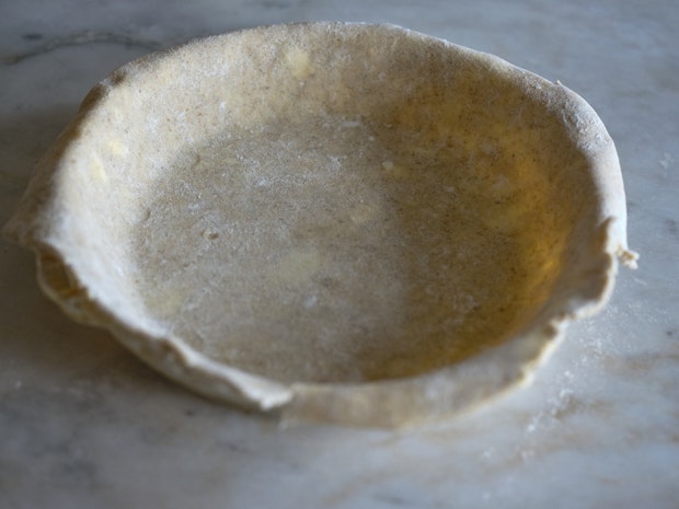 a pie dish lined with pie dough for a bottom crust prior to filling
