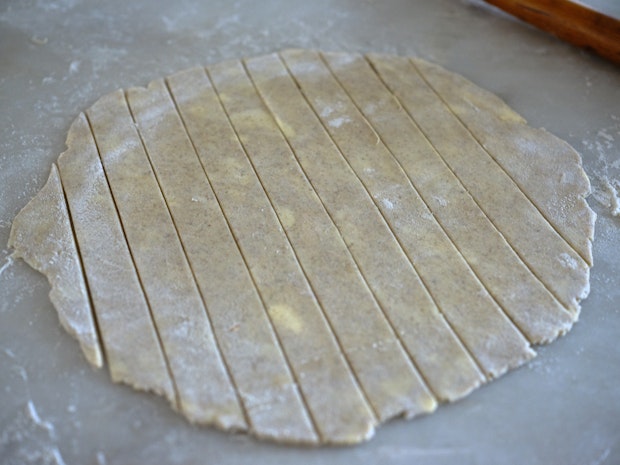 pie dough rolled out on a floured counter and cut into strips
