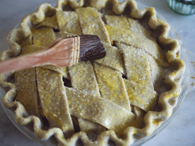 an apple pie before baking being brushed with an egg was and sprinkled with sugar