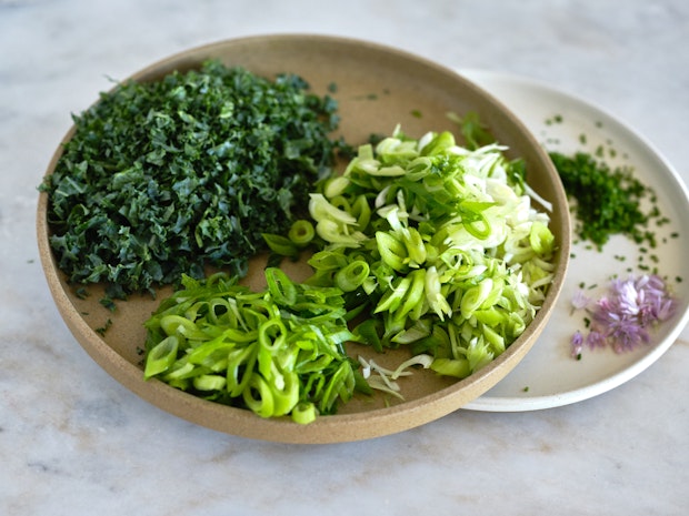 ingredients for sheetpan frittata on plate including chopped green onions, kale, and chives