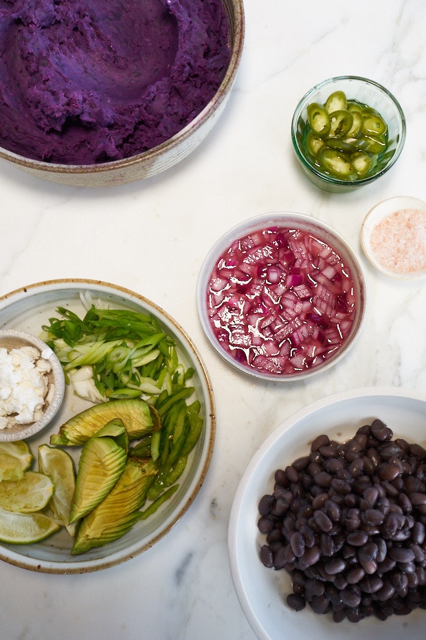 small bowls of sweet potato taco toppings including pickled onions, sliced avocado, black beans