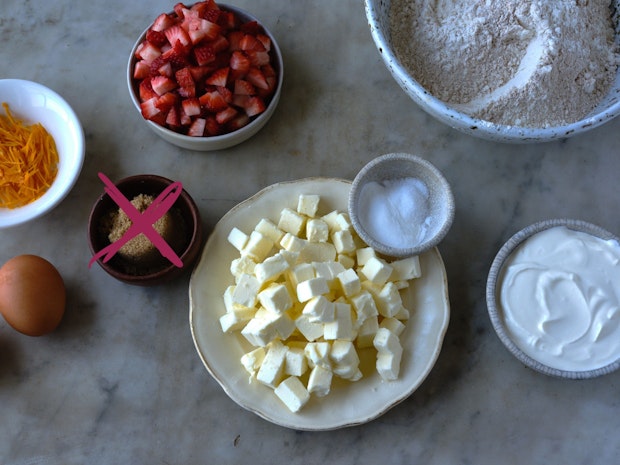 ingredients for making a strawberry scone recipe arranged on a marble counter