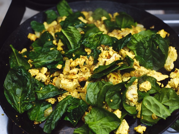 tofu scramble with added spinach in a hot skillet