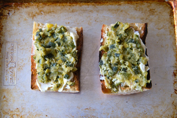 assembling a tomato sandwich starting with mayo and zucchini butter