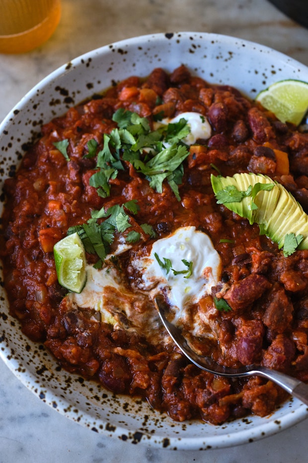 bowl of vegan chili topped with sour cream and avocado