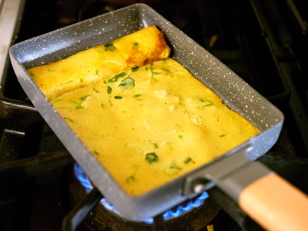 Rolled tamagoyaki cooking in a rectangular pan