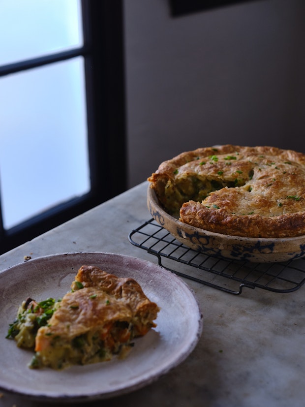 vegetable pot pie on a cooling rack with a slice on a plate nearby