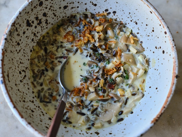 A bowl filled with creamy wild rice soup topped with fried shallots