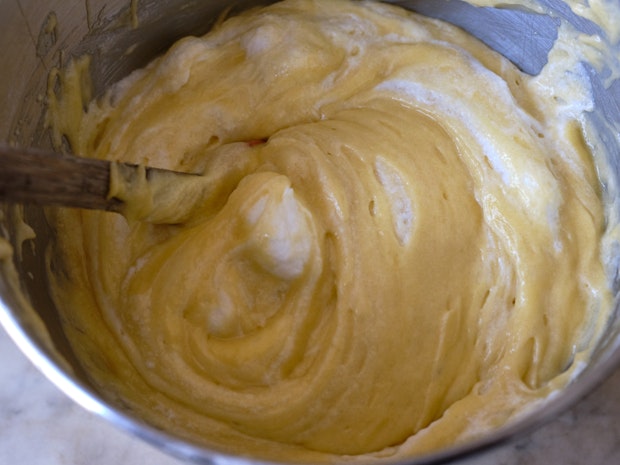 folding whipped egg whites into yellow cake batter in a large mixing bowl