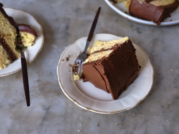 slices of yellow cake with chocolate frosting arranged on a marble countertop