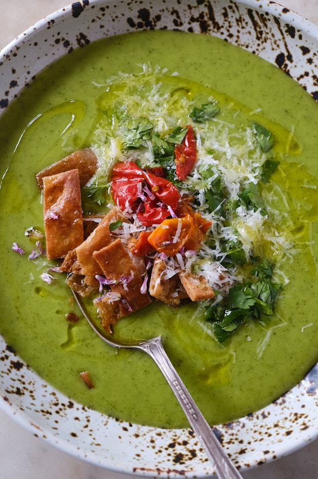 zucchini soup in a bowl with a spoon and toppings